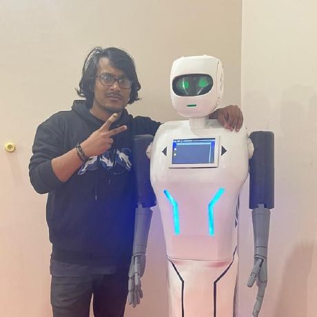 Sihab Sahariar standing next to a white humanoid robot, making a peace sign